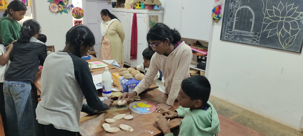Students and a teacher working together on coconut shells at a table full of craft supplies