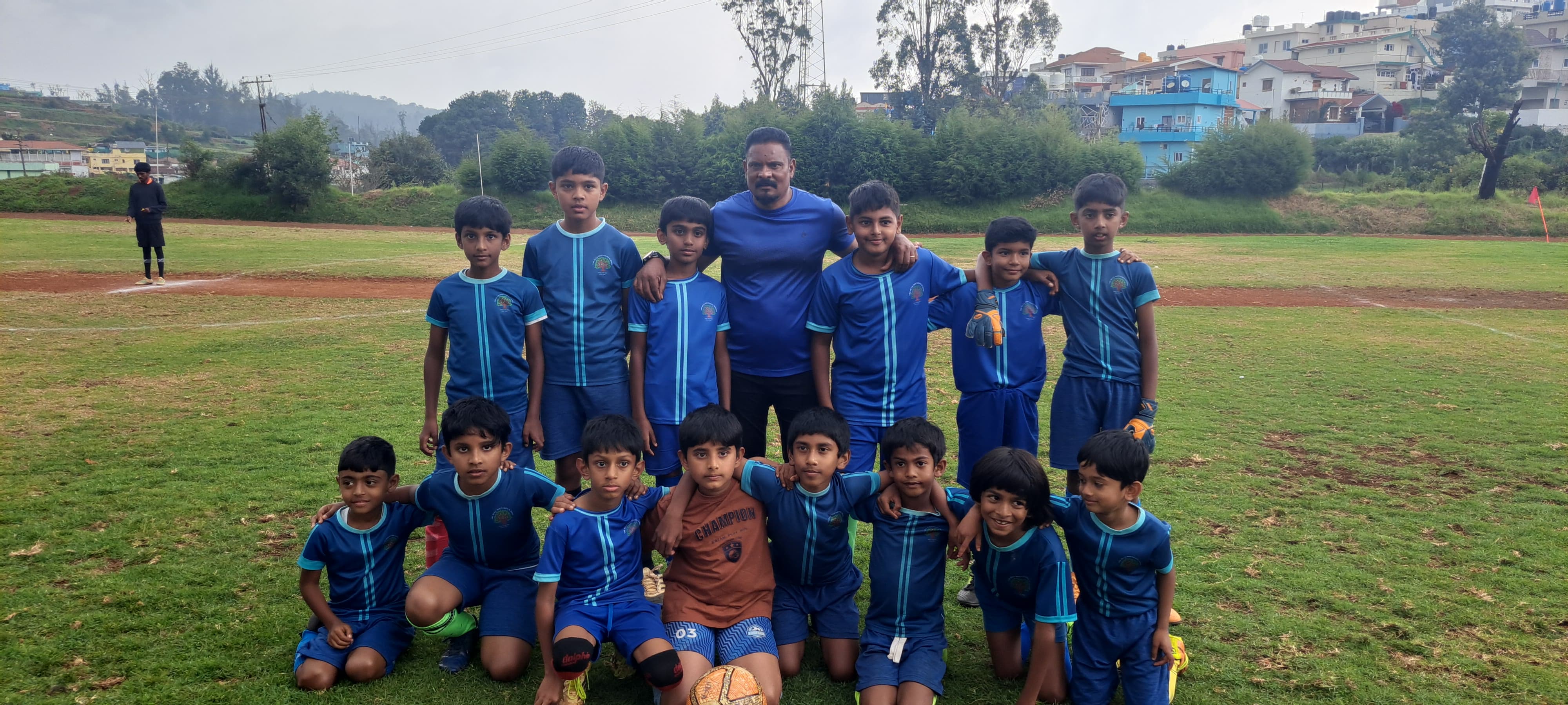 The BMS U10 Blue Cubs football team posing together with their coach on the field
