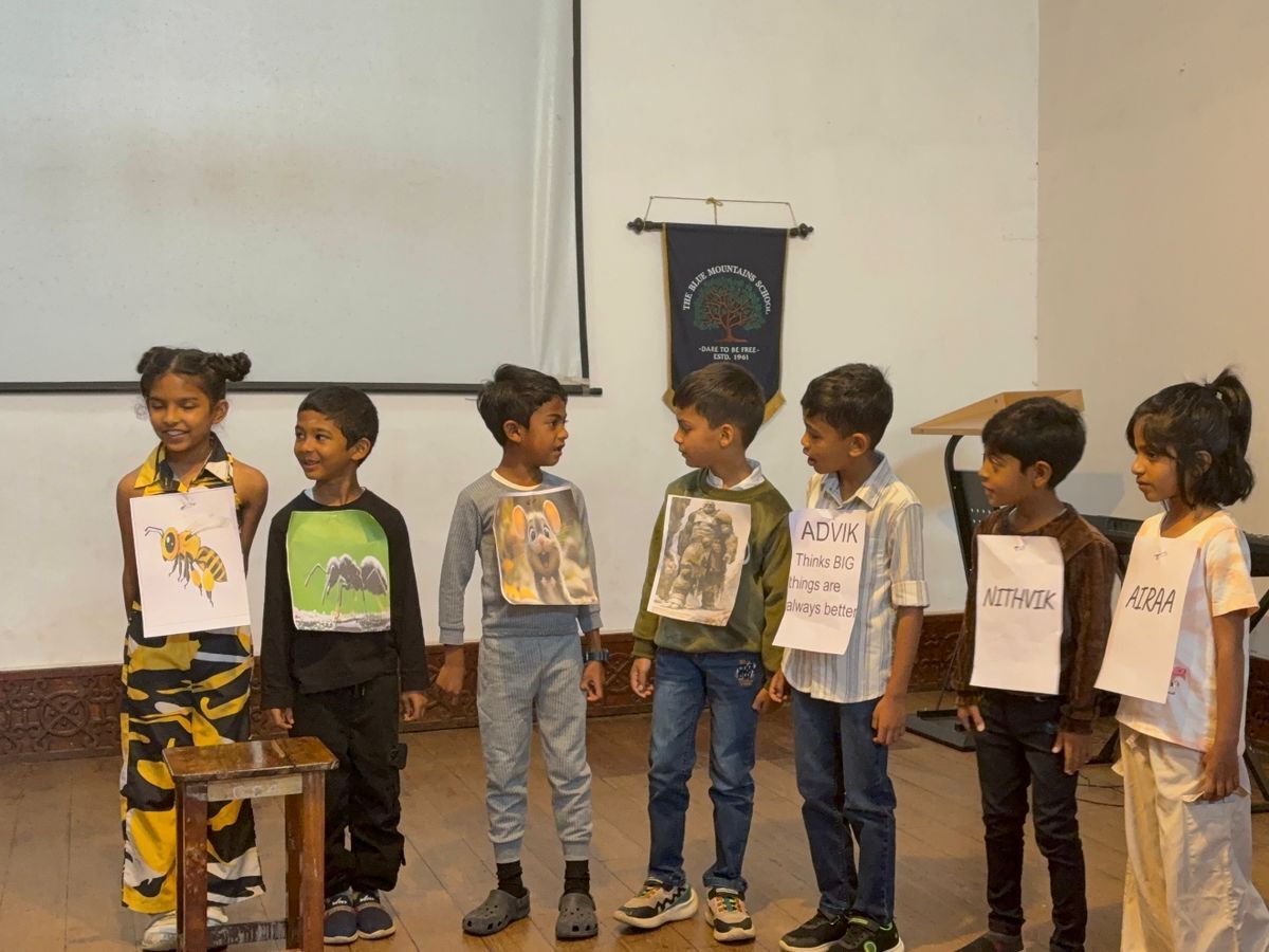 Students dressed as a bee, an ant, a wolf and a bear face Advik, Nithvik and Airaa on stage during the assembly skit at bms