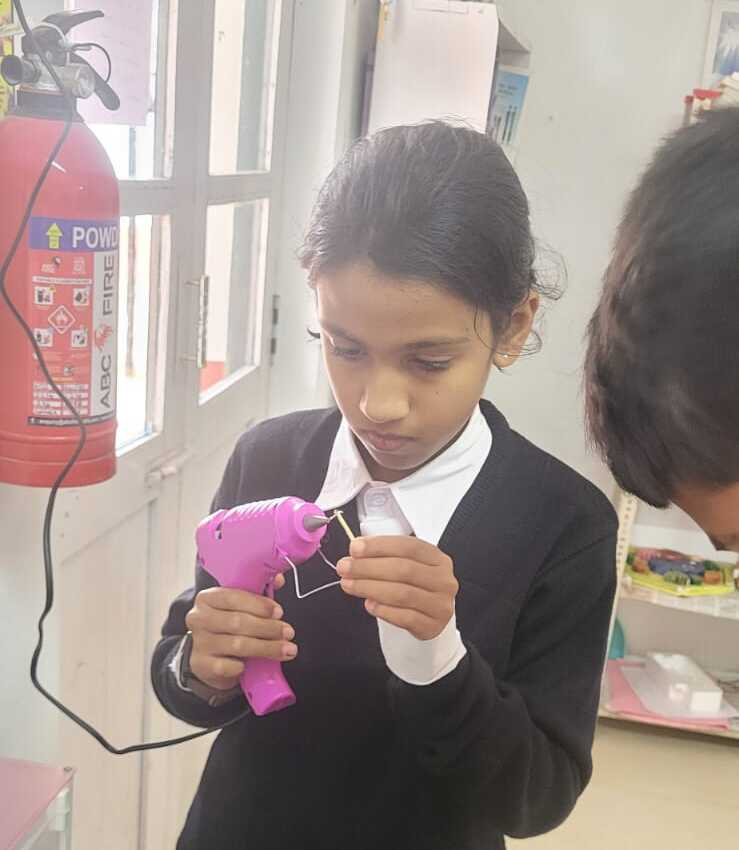 A student using a glue gun to join matchsticks