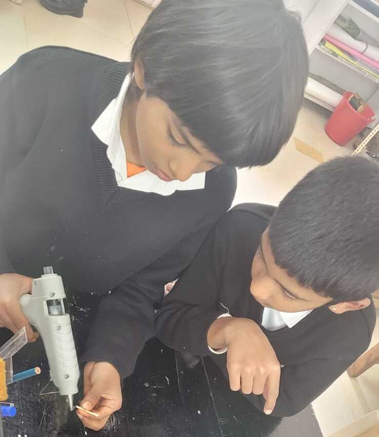 Two students working together with a glue gun
