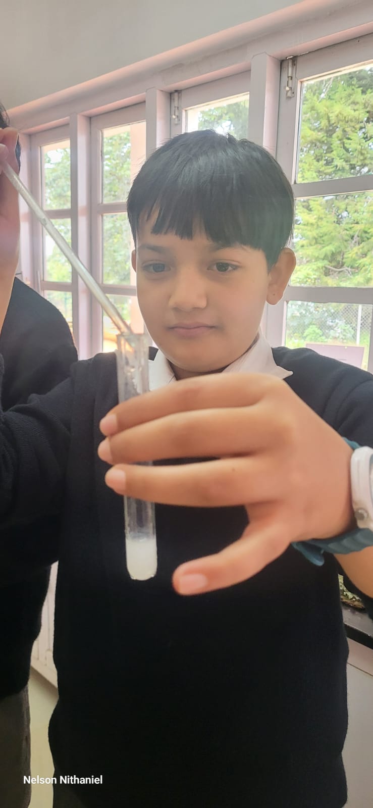 A student holding up a test tube of milky lime water after exhaling into it
