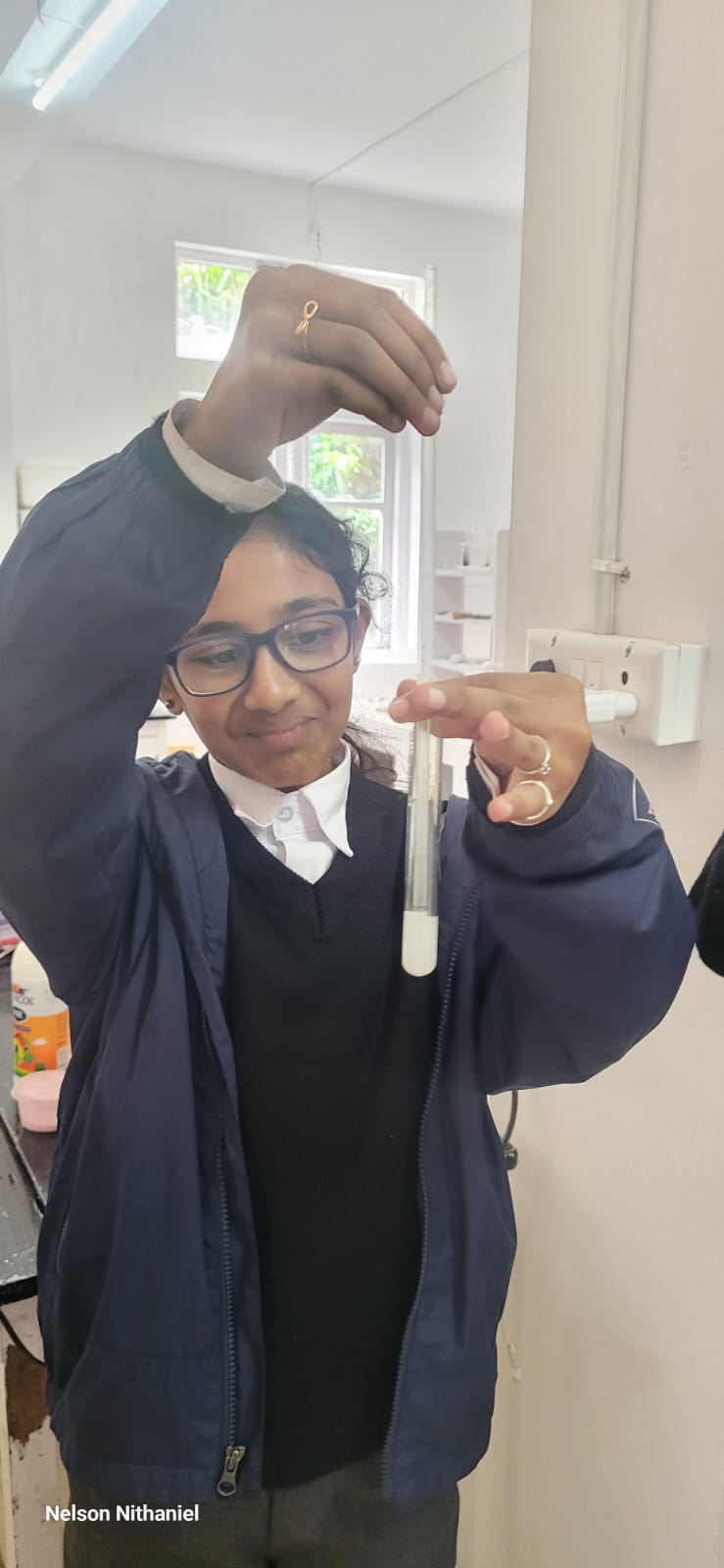 A student holding a test tube of milky lime water up to the light