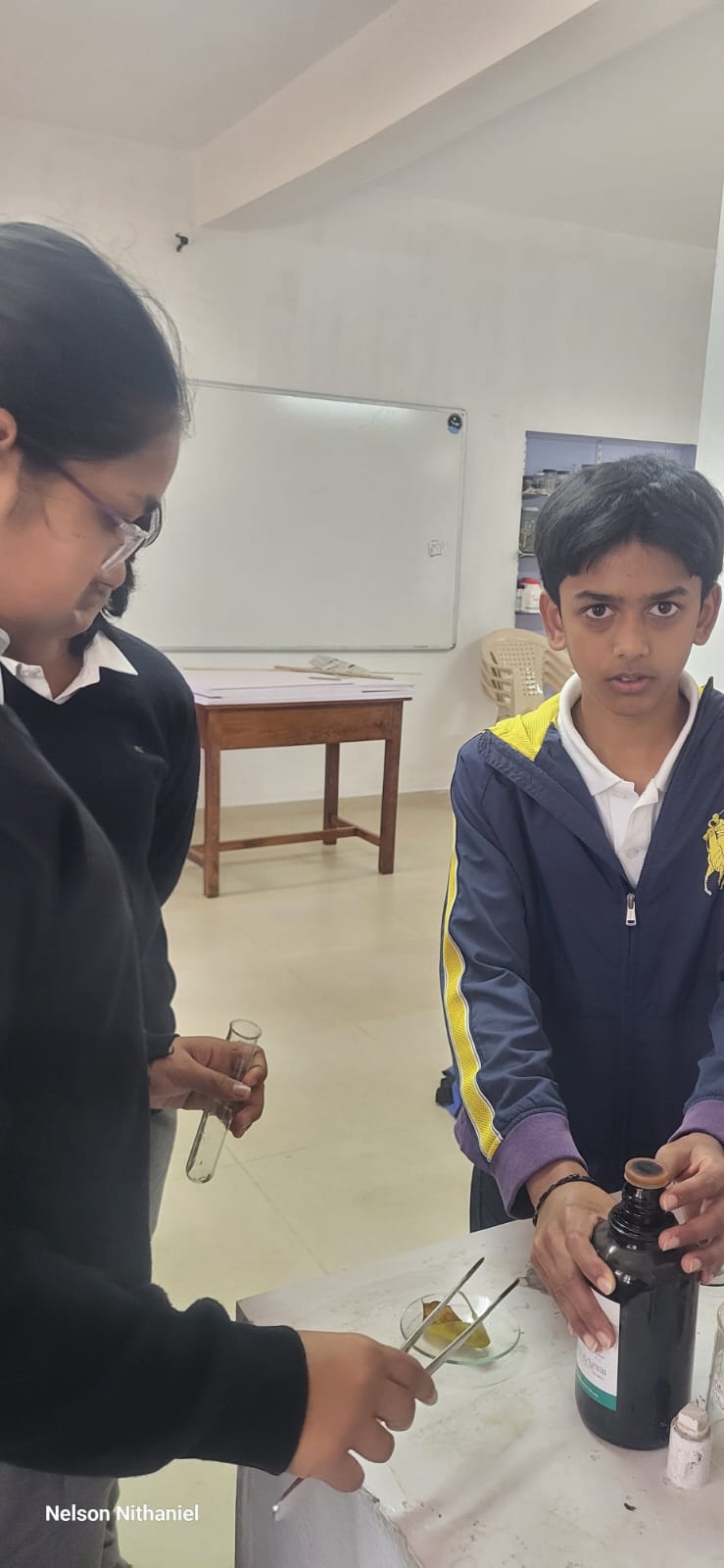 A student holding the bottle of iodine solution while a classmate looks on