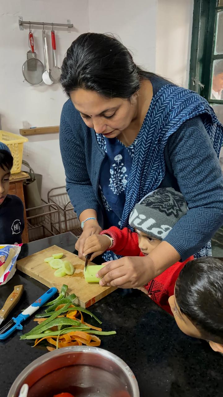 teacher helping a child slice cucumber in culinary class at bms