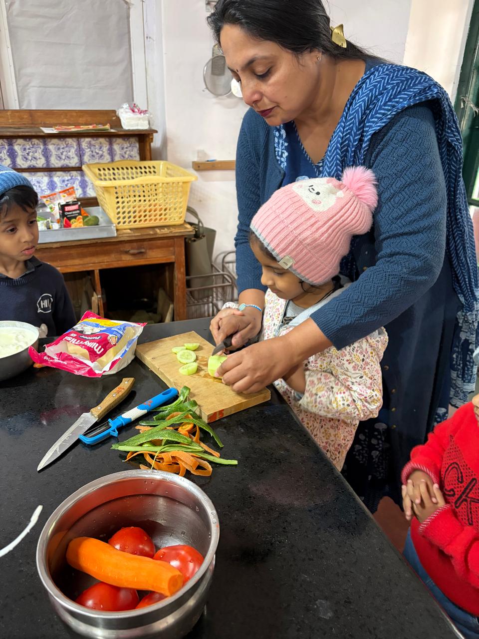 teacher helping a first step child cut cucumber at bms