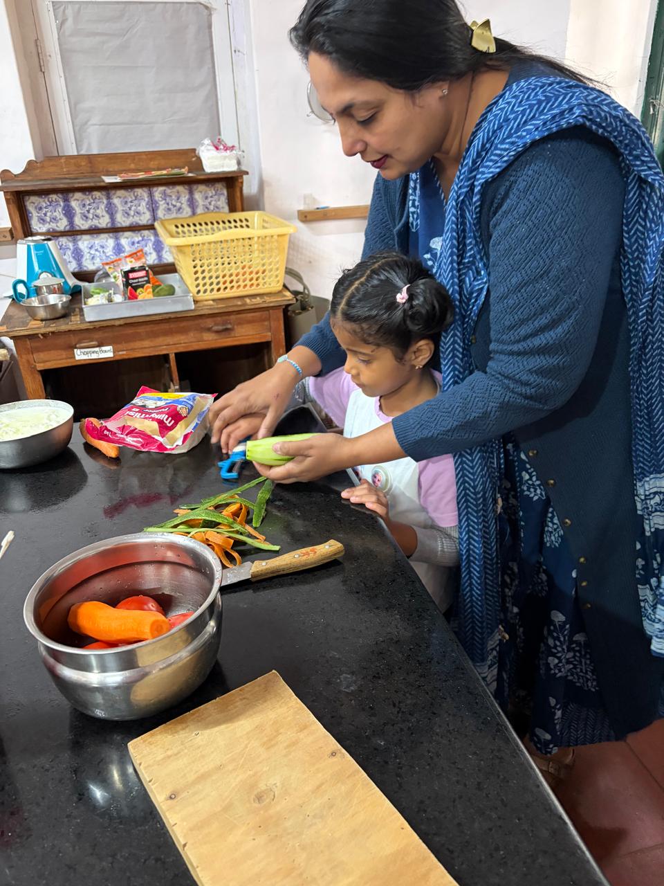 teacher peeling vegetables with a first step child at bms