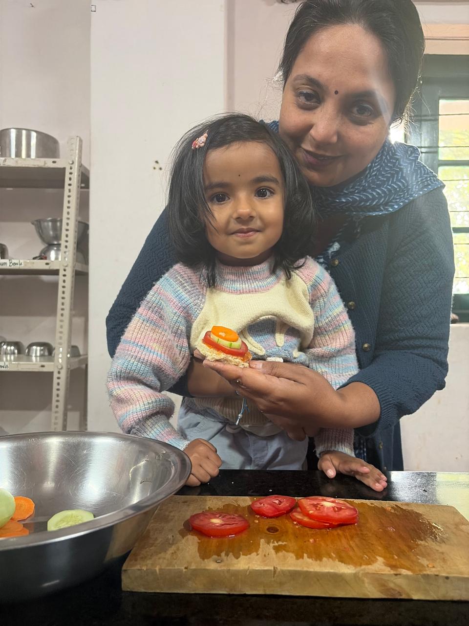 first step child holding a finished sandwich with teacher at bms