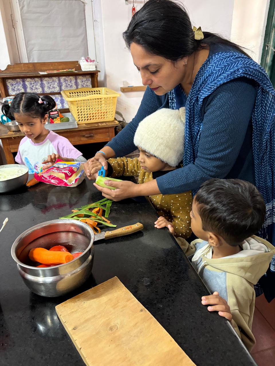 teacher peeling cucumber with first step children at bms